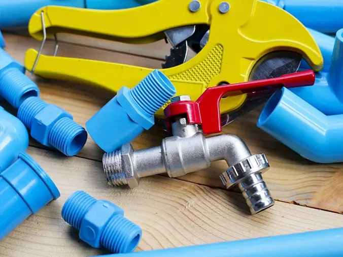 Blue PVC pipe pieces and fittins with a steel valve and PVC cuttin tool