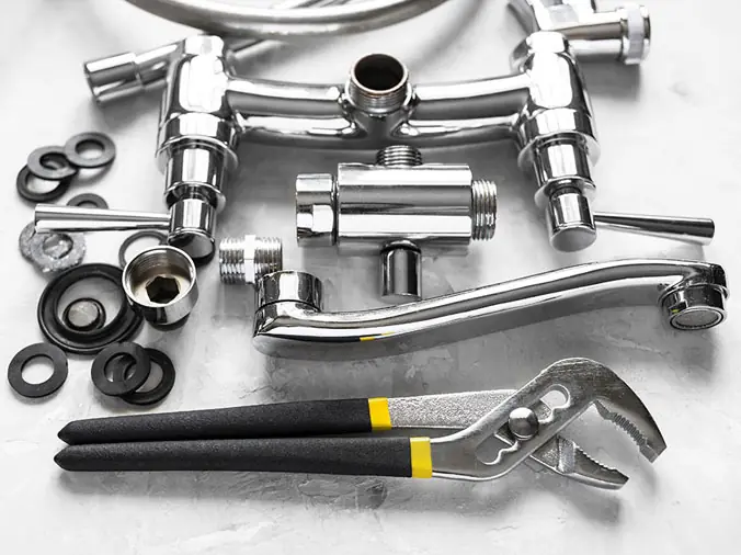 Disassembled chrome kitchen faucet with wrench